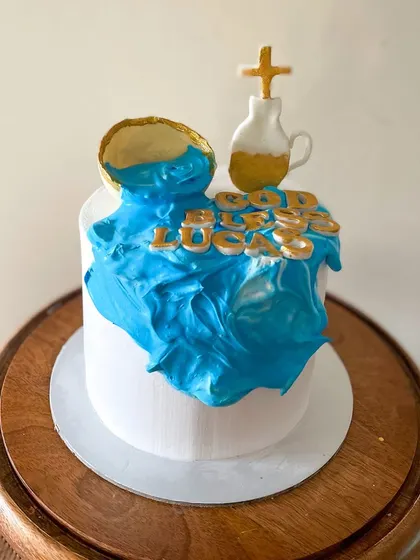 This was a special Holy Communion cake for Lucas, made with whipped cream and minimal fondant. The design creatively uses blue whipped cream to depict water flowing from a chalice, with gold fondant letters for the blessing.