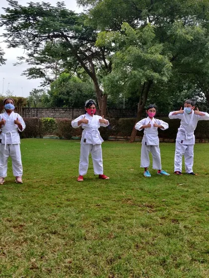 Thumbs up for outdoor karate. This group is feeling proud and energized after a session in the park, showing their enthusiasm for learning martial arts together.