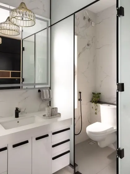 A well-designed bathroom combines luxury with functionality. This vanity and bath area features clean lines, marble-patterned walls, and a frosted glass partition for privacy. Smart storage within the vanity and elegant fixtures from Kohler complete this modern and serene personal space.