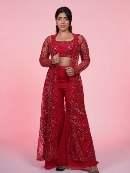 The red three-piece set is all about making a statement. The combination of the crop top, wide-leg pants, and sheer jacket is modern and glamorous.
