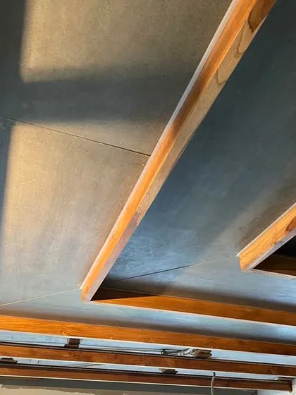 A detail of the ceiling structure in the Lucknow penthouse during construction. The image shows the interplay between the exposed concrete slab and the custom wooden beams that define the geometry of the space.