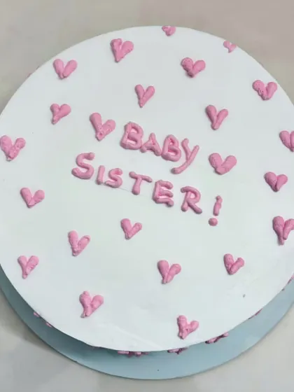 A sprinkle of sweetness and a pop of pink! This simple 'Baby Sister' cake with tiny hearts is perfect for celebrating a special sisterly bond.