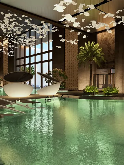 A woman relaxes in the luxurious pool at Palais Royale. The design features private cabanas, expansive decks, and soft lighting from a bespoke overhead installation, creating an experience where luxury is taken to the next level.