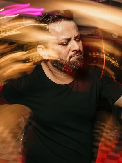 A high-energy shot of a guest lost in the music on the dance floor, captured with a slow shutter to create dramatic light trails.