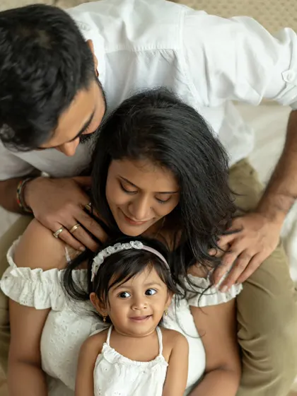 A beautiful overhead shot of a family of three. The daughter looks up at the camera with a sweet smile, creating a unique and engaging perspective.