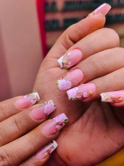 A garden at your fingertips. This beautiful design features delicate pink cherry blossoms with gold leaf accents, painted over a modern French tip base.