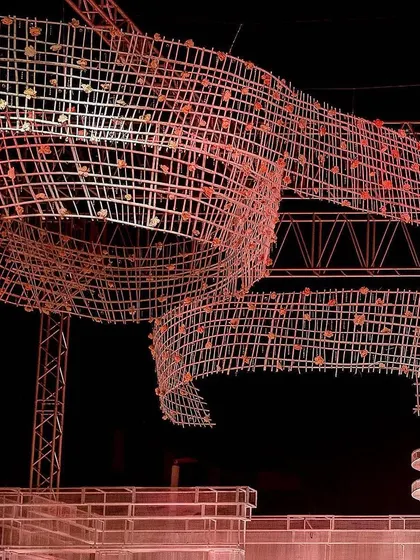 The overhead ribbon installation illuminated in a soft pink light. Each intersection of the woven structure was dotted with floral details, adding another layer of texture and romance to the design.