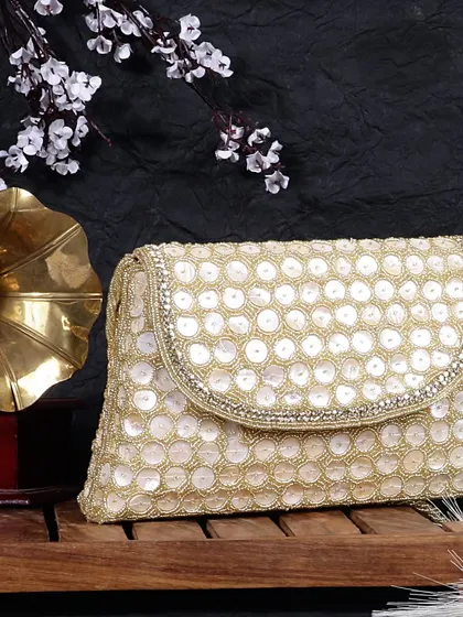 A vintage inspired lifestyle shot of a handcrafted beaded clutch. The gramophone and dark wood create a timeless, elegant setting that speaks to the bag's classic appeal.