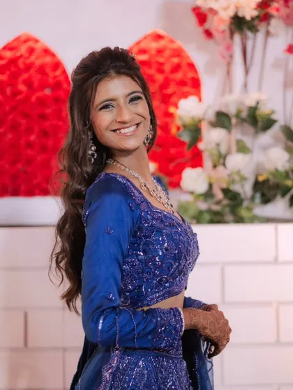 A bright and happy client in a royal blue outfit. Her makeup is fresh and radiant, with a big smile that says it all.