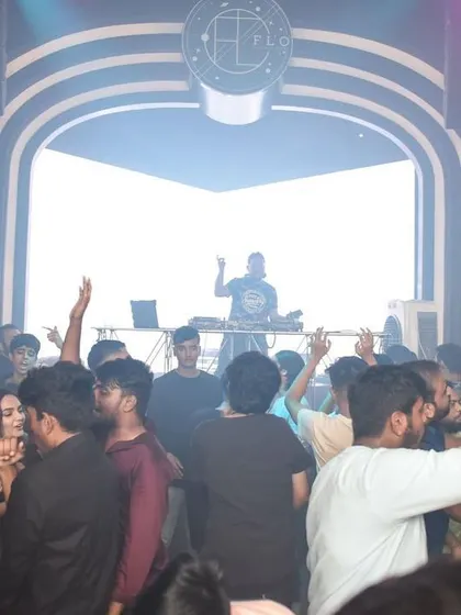A view from the back of the club, showing the dance floor packed with people enjoying the music under the stage lights.