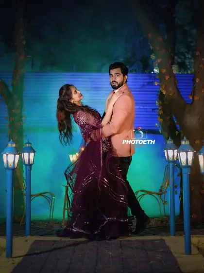 A romantic dance dip captured at night. The blue backlighting and path lined with lanterns create a magical, cinematic setting for this pre-wedding shot.