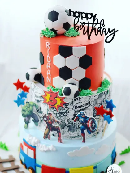 For the kid who loves everything. This three-tier cake combines a football theme, an Avengers comic strip, and a toy train, creating a truly personalized and action-packed birthday centerpiece.