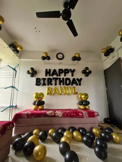 A full room view of the birthday decoration, with black and gold balloons scattered on the floor and ceiling.