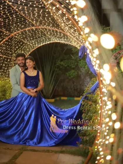 A couple framed by an arch of lights, with the woman in a royal blue flying gown. The man's light-colored blazer provides a nice contrast, making the couple stand out in the evening setting.
