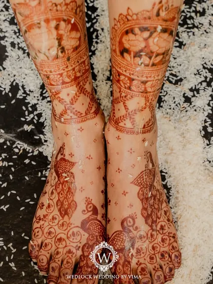 The beauty of Mehendi is in the details. This intricate floral henna design is perfectly complemented by a backdrop of fresh pink and white roses, showcasing a blend of tradition and artistry.