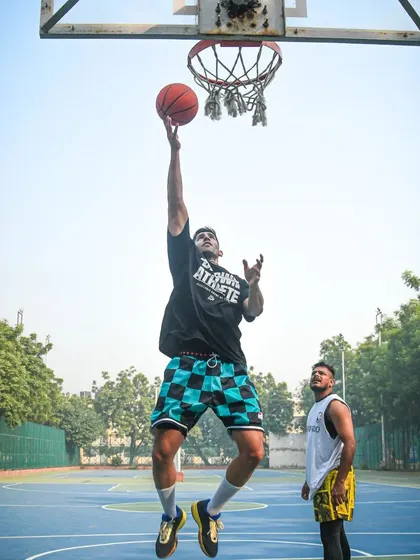 A player flying in for a layup during a group workout. I'm there watching, ready to give feedback.