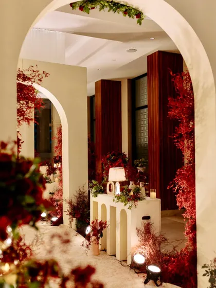 A beautifully lit corner of the reception, with a modern console table, a table lamp, and red floral arrangements creating a warm and inviting nook.