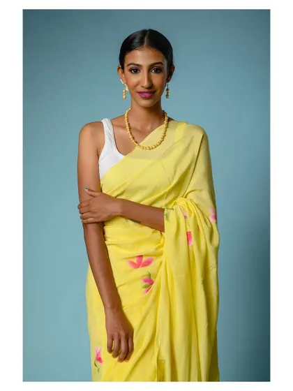 A close-up portrait of the model in the yellow saree, giving a better view of the neckline and jewelry.