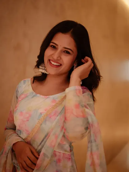 A happy and bright portrait of actress Brinda Acharya. The simple background and warm lighting keep the focus entirely on her radiant smile and traditional earrings.
