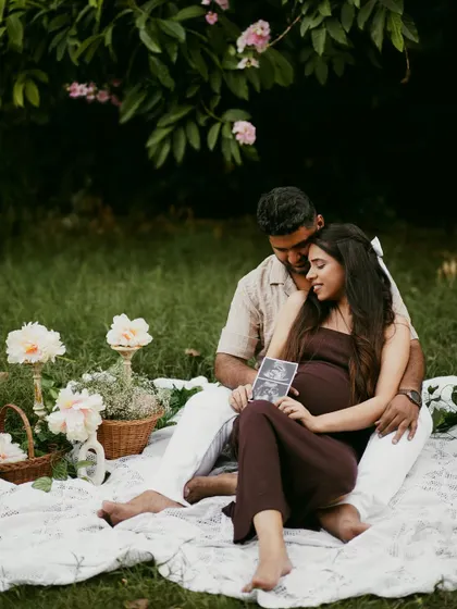 A romantic outdoor picnic scene, where the couple looks at their sonogram pictures together.