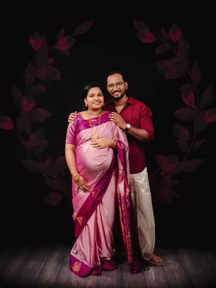 A beautiful, formal portrait celebrating South Indian tradition. The couple is dressed in a stunning pink silk saree and a classic veshti, creating a culturally rich and memorable maternity photograph.