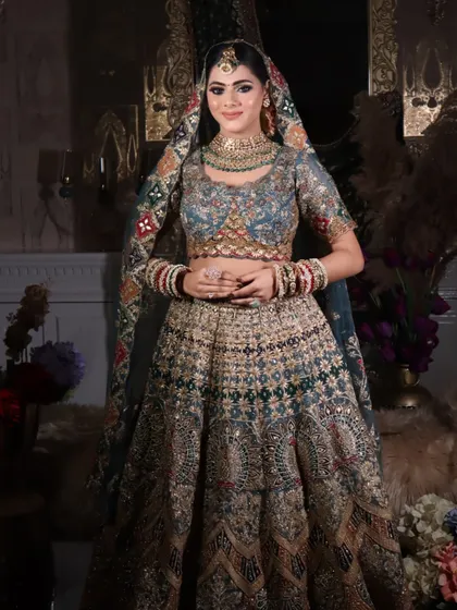 A standing portrait of the bride, showcasing the full lehenga and the beautiful, multi-colored dupatta. The makeup is designed to stand out and complement the detailed outfit.