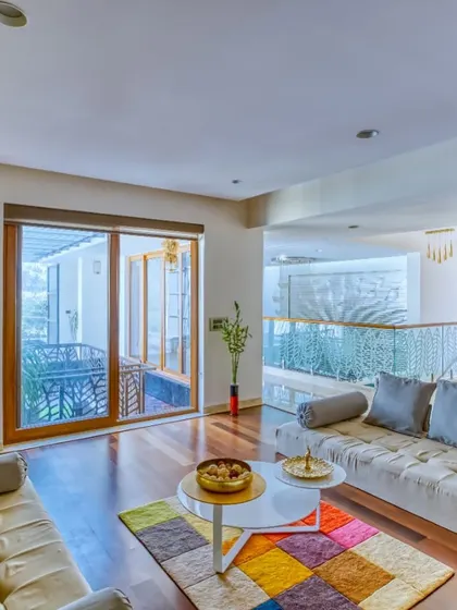 A family lounge area in "A Home by the Park." The space is designed for informal gatherings, with comfortable seating and a connection to an outdoor balcony.