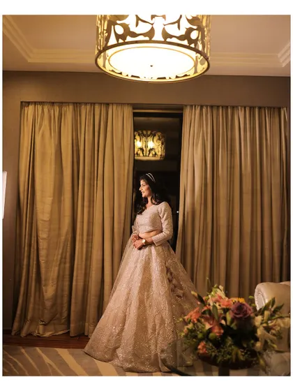 The bride-to-be, looking out in a moment of quiet reflection before the engagement ceremony. Her stunning gown and the warm lighting create a beautiful, dreamy portrait.