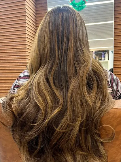 A stunning example of a balayage with a mix of brown and lighter caramel tones. The soft waves emphasize the beautiful blend of colors, creating a look full of dimension and texture.
