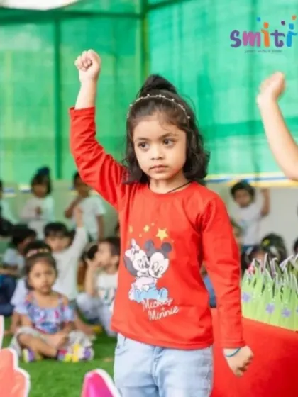 A young performer stands confidently on stage, her arm raised in a powerful pose. Our events give every child a chance to shine.