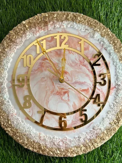 A delicate and pretty clock with a pink and white marble design and a full border of gold and white crystals.