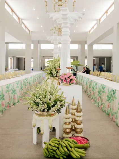 A traditional dining setup for a Bhaat ceremony, with long tables and floral arrangements featuring tuberoses.