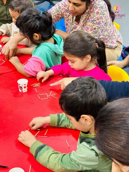 Children work together on a matchstick puzzle, learning about shapes and spatial relationships. This collaborative activity also teaches teamwork and communication.