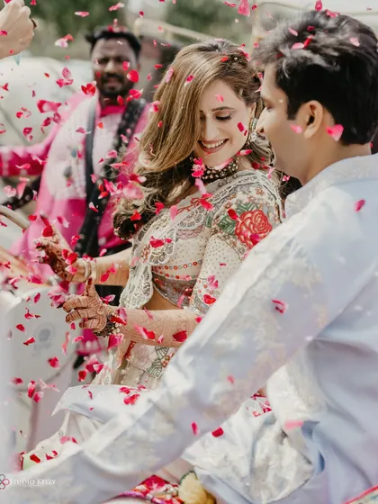 A shower of rose petals rains down on the couple as they enjoy their grand entry in a horse-drawn carriage.