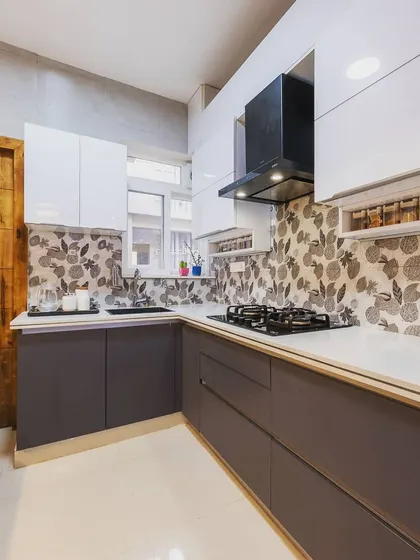 A two-tone kitchen with dark grey base cabinets and white upper cabinets. The floral patterned backsplash adds a touch of personality and charm to the space.
