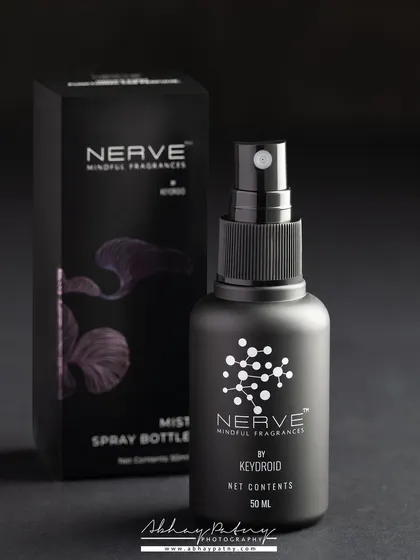A minimalist and sophisticated shot for a mist spray bottle. The dark, monochromatic theme emphasizes the sleek packaging and modern branding, appealing to a design-conscious audience.