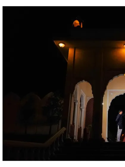 A wide shot capturing the bride and groom dancing, framed by the arches of the venue at night. This image focuses on the romantic atmosphere of the celebration.