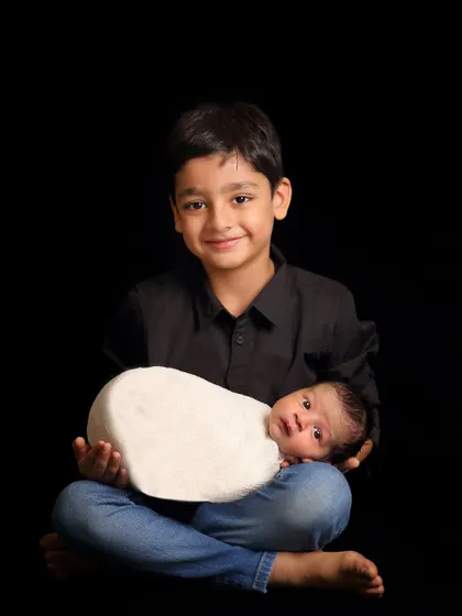 A classic sibling portrait against a simple black background. This style puts all the focus on the children's expressions and the bond between them.