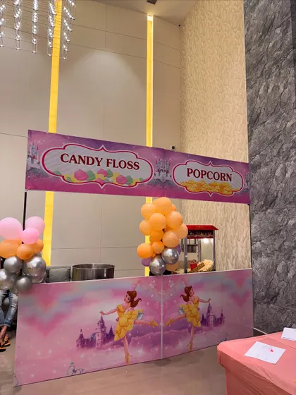 A classic candy floss and popcorn stand with a princess theme, adding a fun and sweet touch to a baby welcome ceremony.