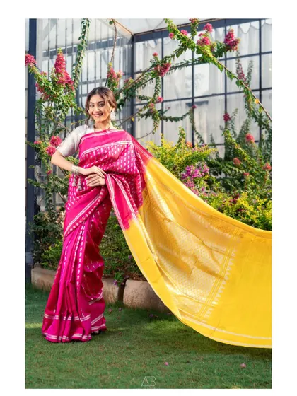 A joyful, dynamic portrait in a beautiful garden. The movement of the bright yellow and pink saree creates a sense of energy and celebration.
