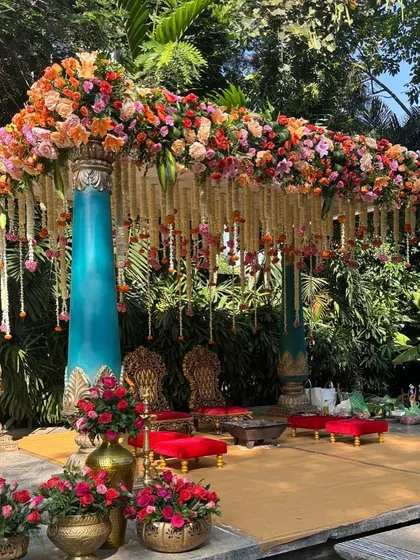 This stunning mandap combines vibrant, multi-colored florals with grand turquoise pillars, perfect for a colorful and celebratory outdoor wedding.