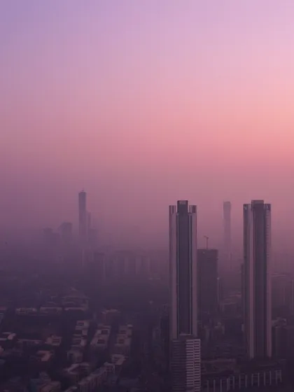 A close-up on two skyscrapers piercing through a thick, purple haze during a Mumbai winter sunset.
