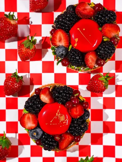 A flatlay of two berry tarts on a red and white checkered pattern. The graphic composition and vibrant colors create a bold and playful image, perfect for social media.