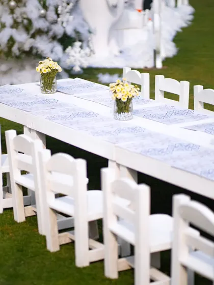 A long, white table set up for the little guests, complete with small chairs and simple floral centerpieces, fitting the clean, wintry theme.