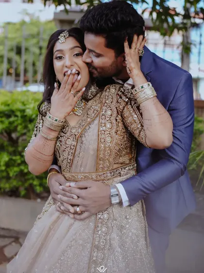 A playful and intimate moment where the groom playfully nibbles the bride's cheek, capturing their fun-loving connection.