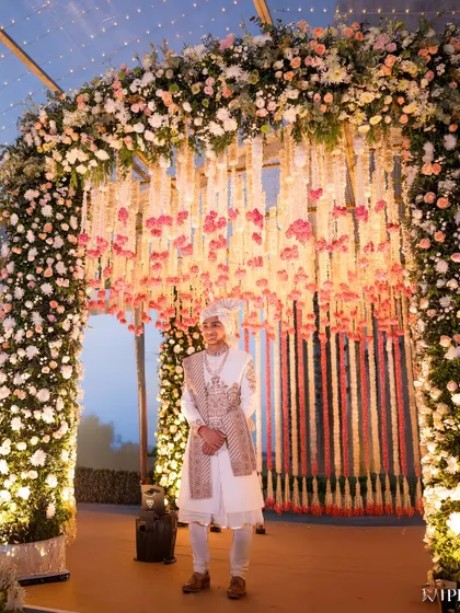 The groom waiting patiently under the magnificent floral arch. The anticipation and excitement in this moment are palpable.