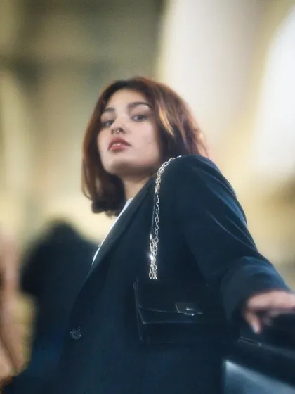 A soft-focus, moody portrait of a woman on an escalator, looking up at the camera. The motion blur and warm tones give this shot a transient, film-like quality.