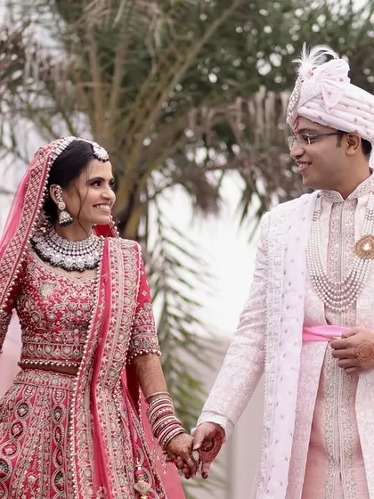 A close-up shot of the couple walking hand-in-hand, focusing on their happy expressions and the detailed craftsmanship of their wedding attire.