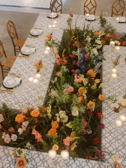 A unique table layout where a river of wildflowers and greenery runs through the center. This creative tablescape design brings the garden directly to the guests' dining experience.