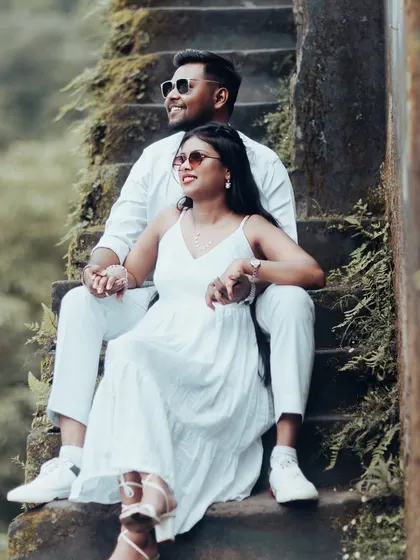 A romantic shot of a couple sitting on old stone steps, their coordinated white outfits creating a clean and timeless look.